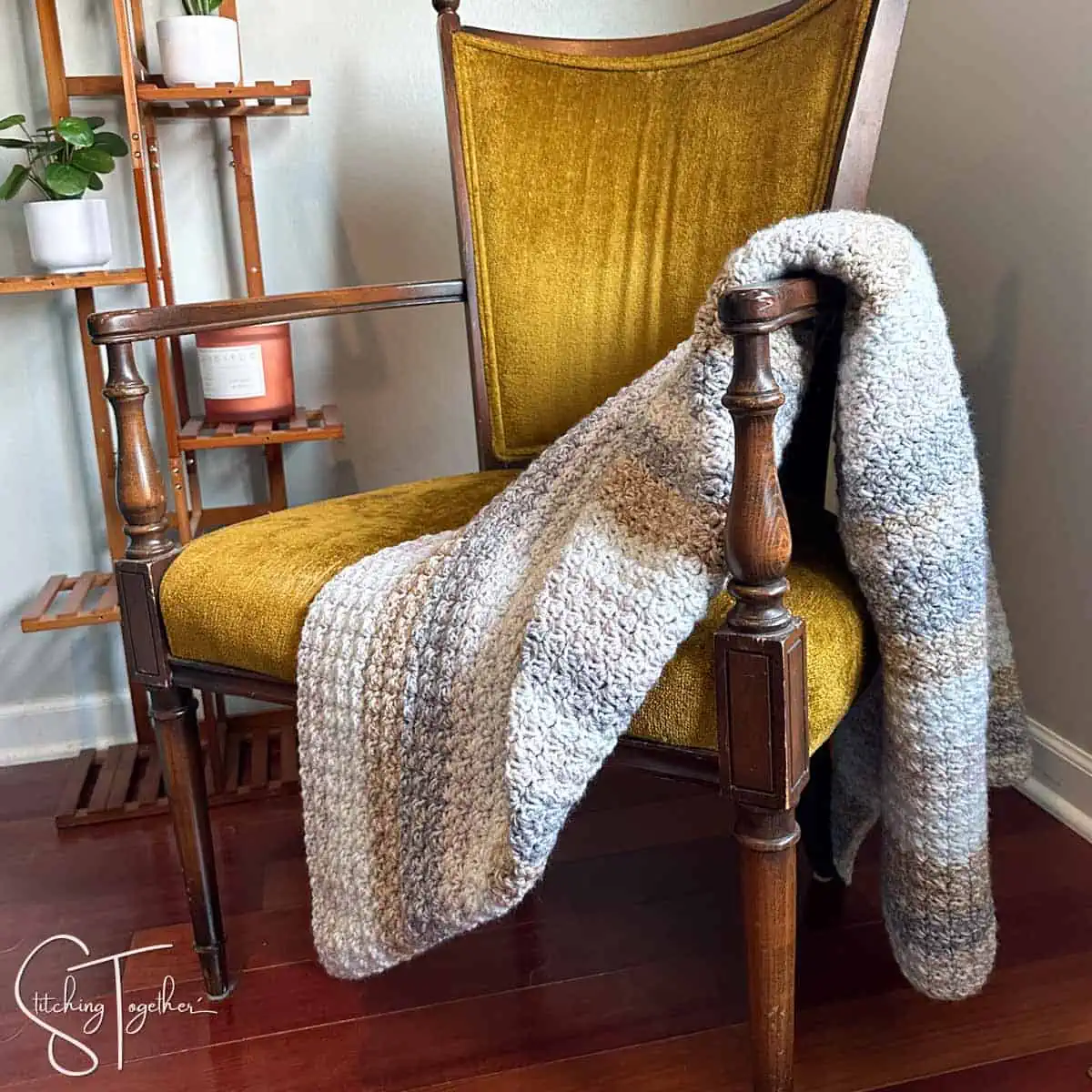 striped suzette stitch crochet blanket draped on the arm of a yellow chair