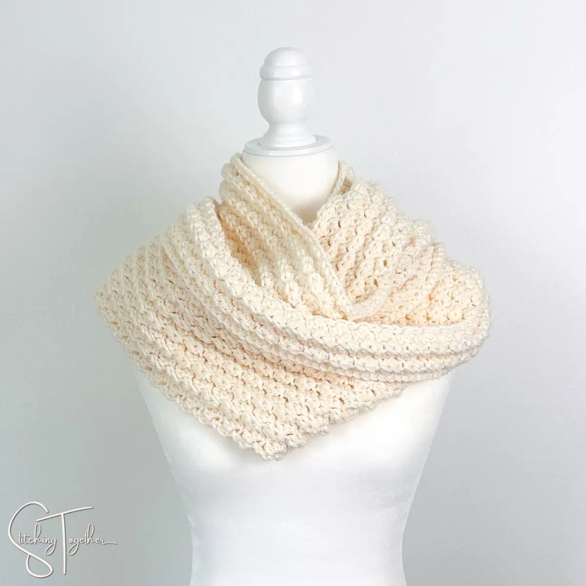 beautifully textured crochet scarf wrapped around the neck of a mannequin