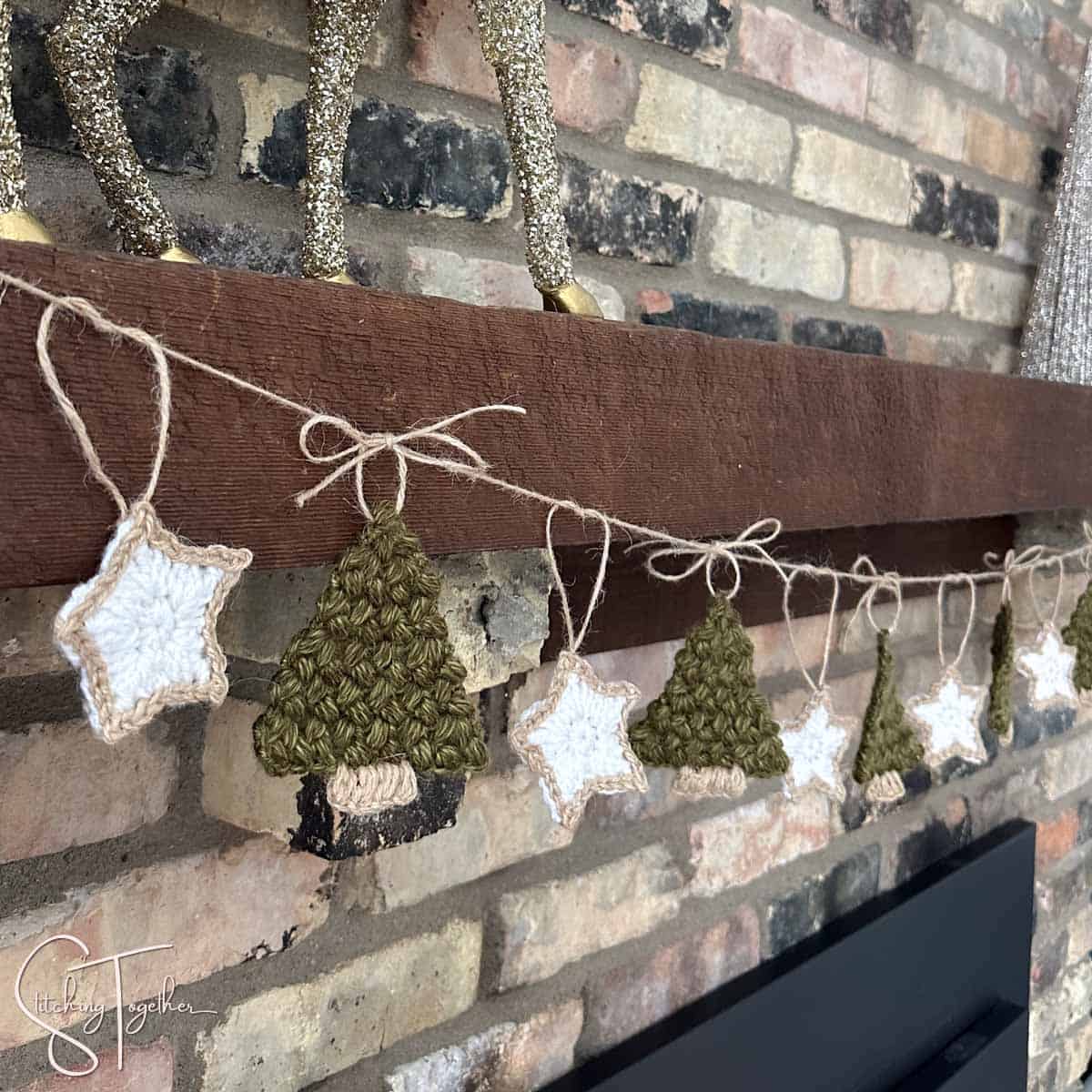 close up of a a Christmas tree crochet garland with stars hanging on a decorated mantle