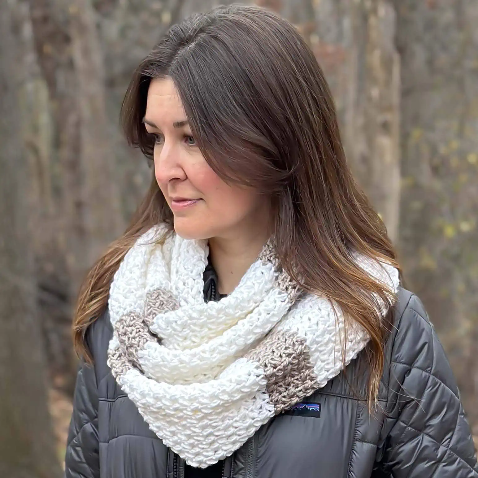 woman outside wearing a white and tan striped and textured crochet infinity scarf