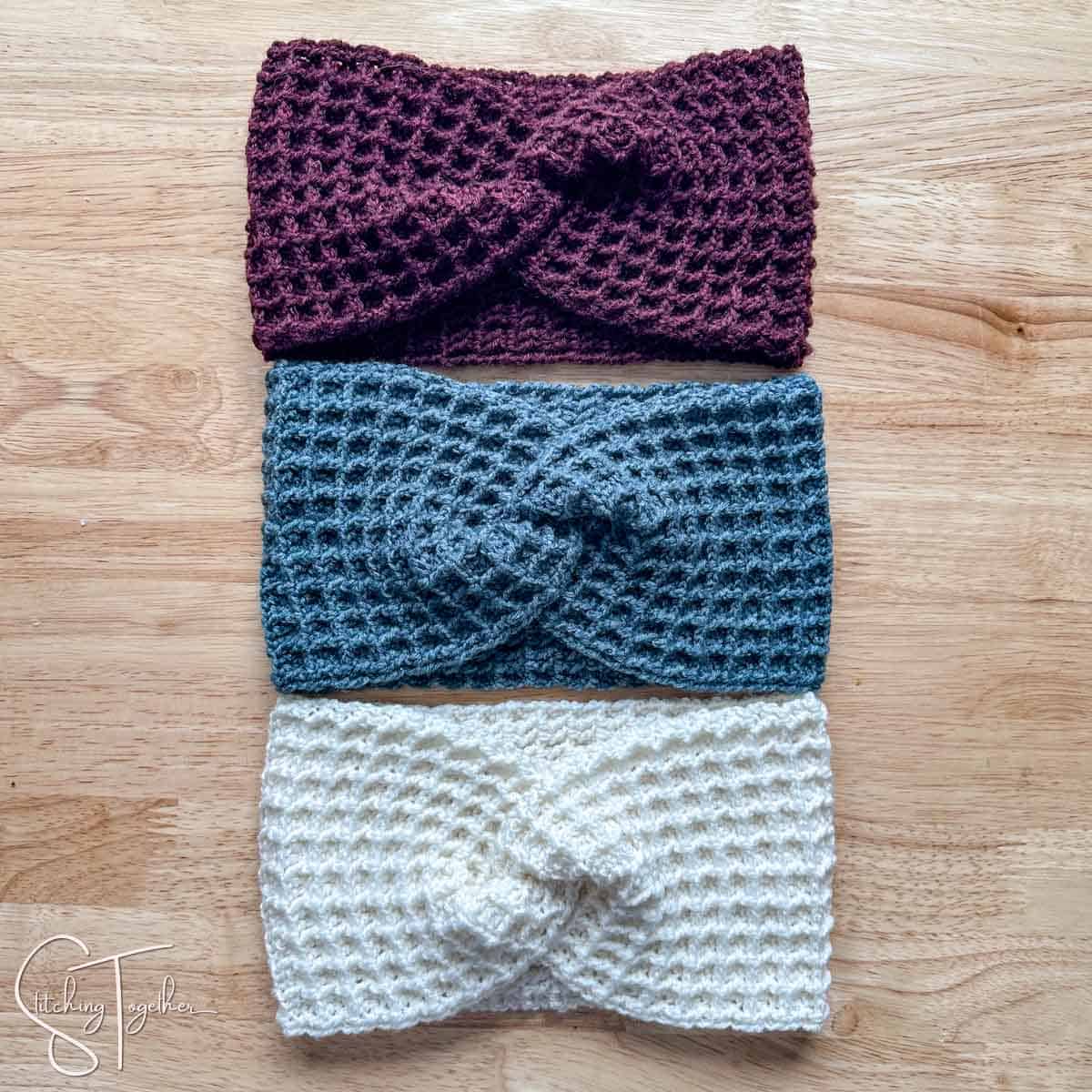three twisted waffle stitch ear warmers laying flat