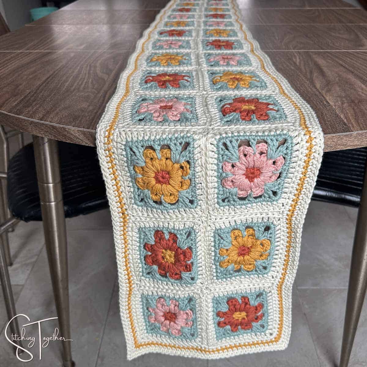 colorful floral granny square table runner hanging off the end of a table