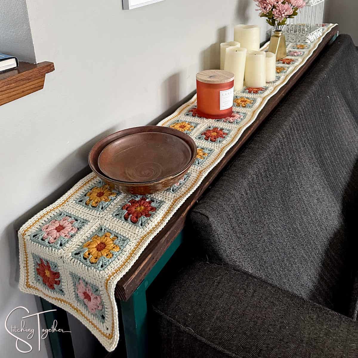 decorated sofa table with a boho crochet table runner on it