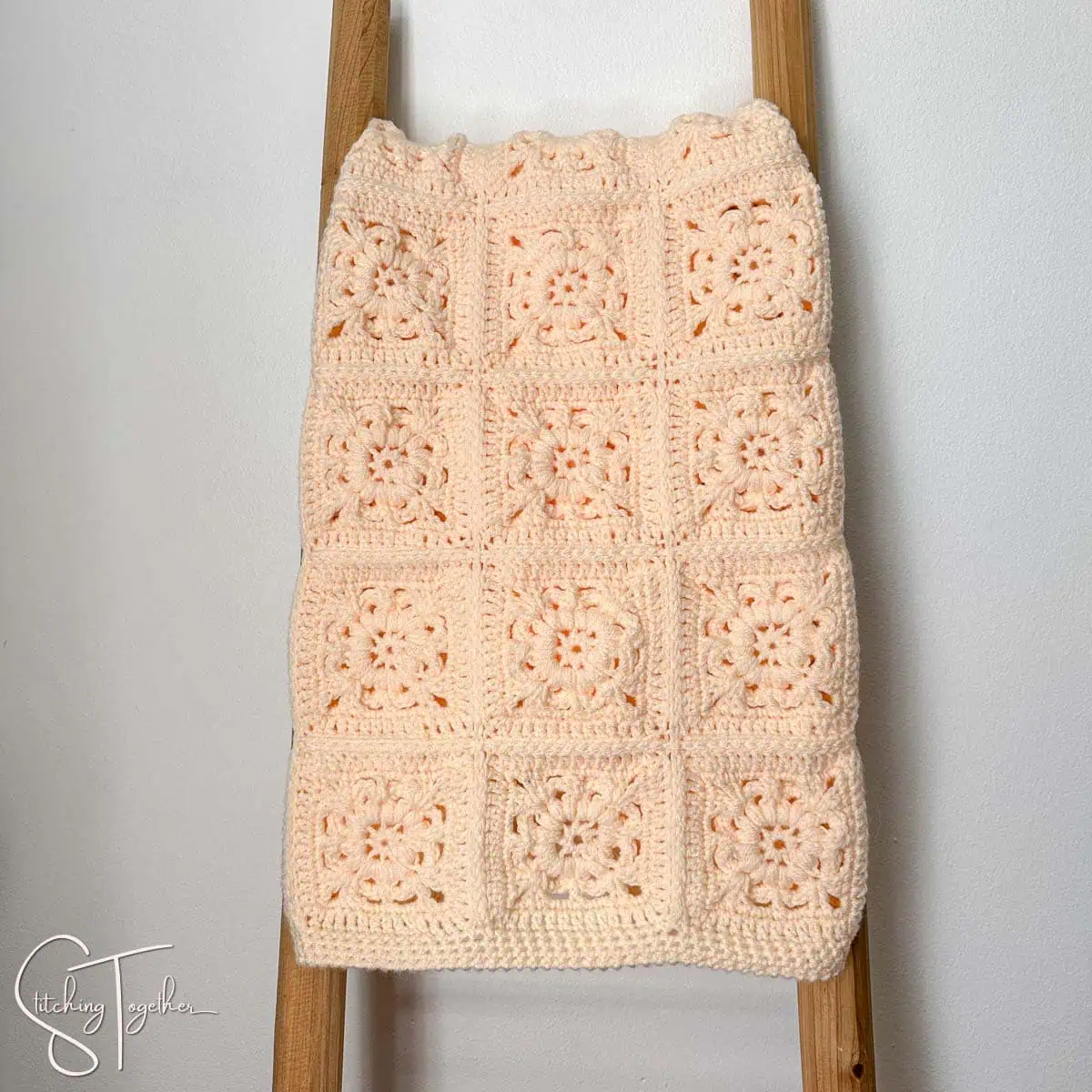 granny square baby blanket folded on a blanket ladder