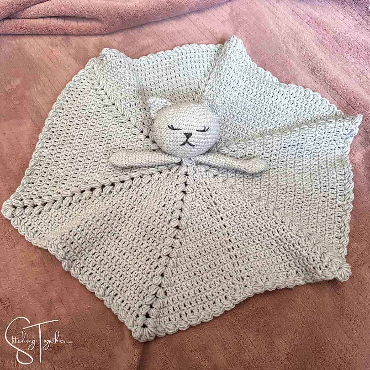 crochet cat lovey fanned out on a blanket