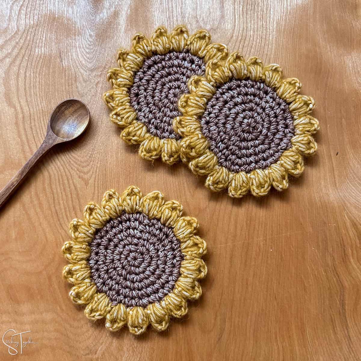 3 crochet sunflowers and a wooden spoon