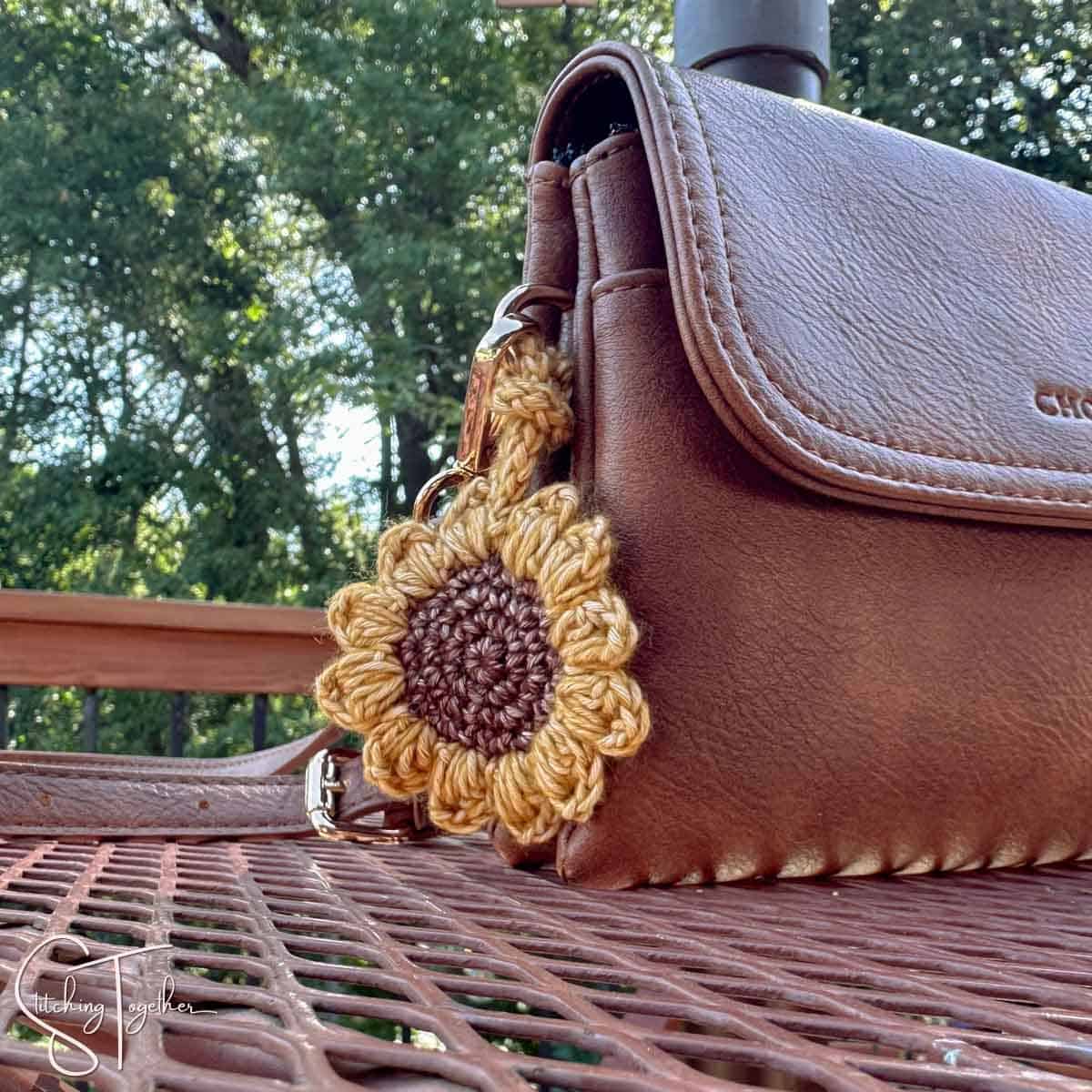 crocheted sunflower hanging on the side of a small purse
