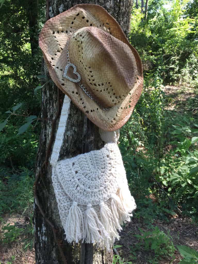 boho crochet bag with fringe hanging from a tree