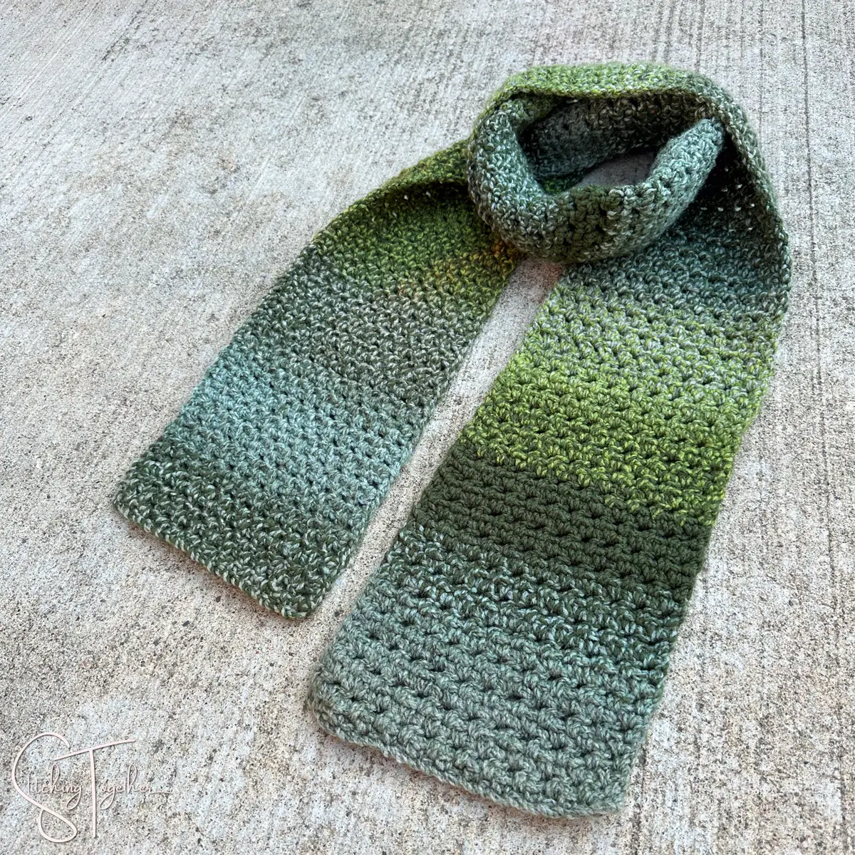 a striped mossy green scarf laying styled on the ground