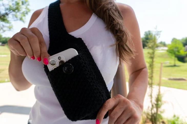 woman pulling a phone out of a black crochet bag