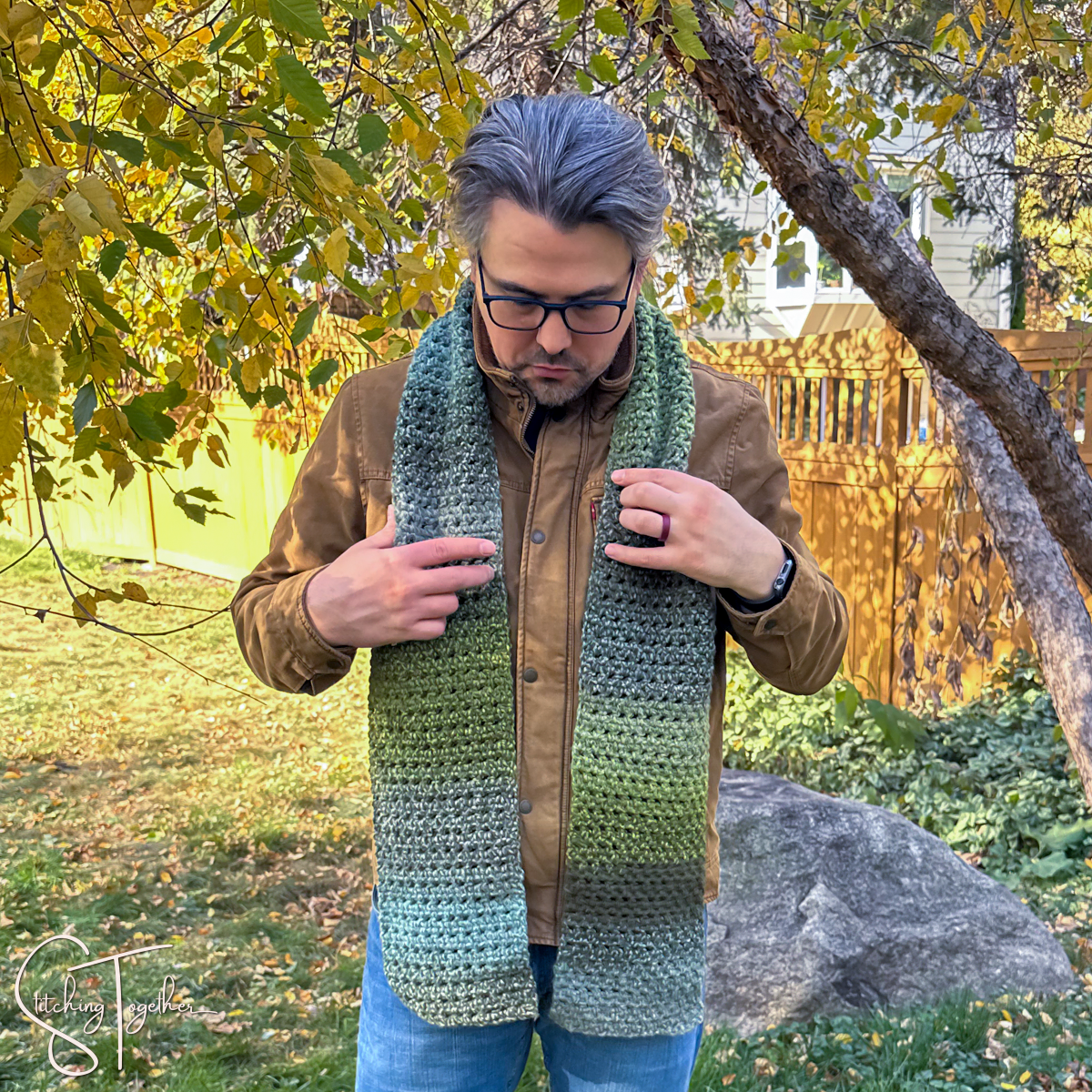 man adjusting the crochet scarf he's wearing
