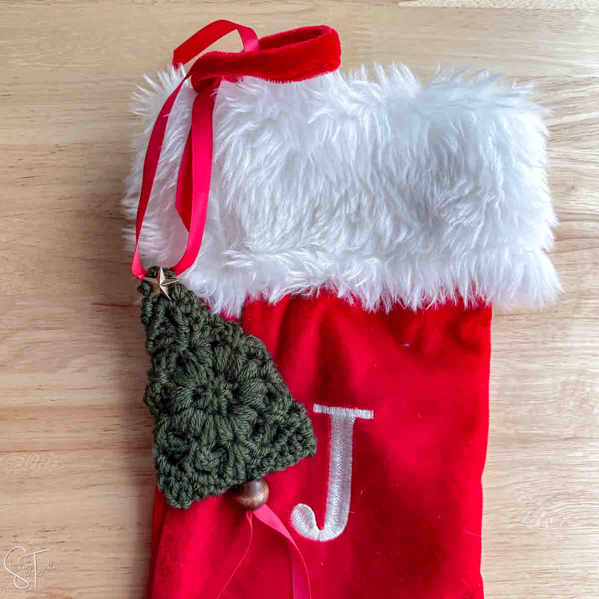 crochet small Christmas tree tied on the top of a stocking