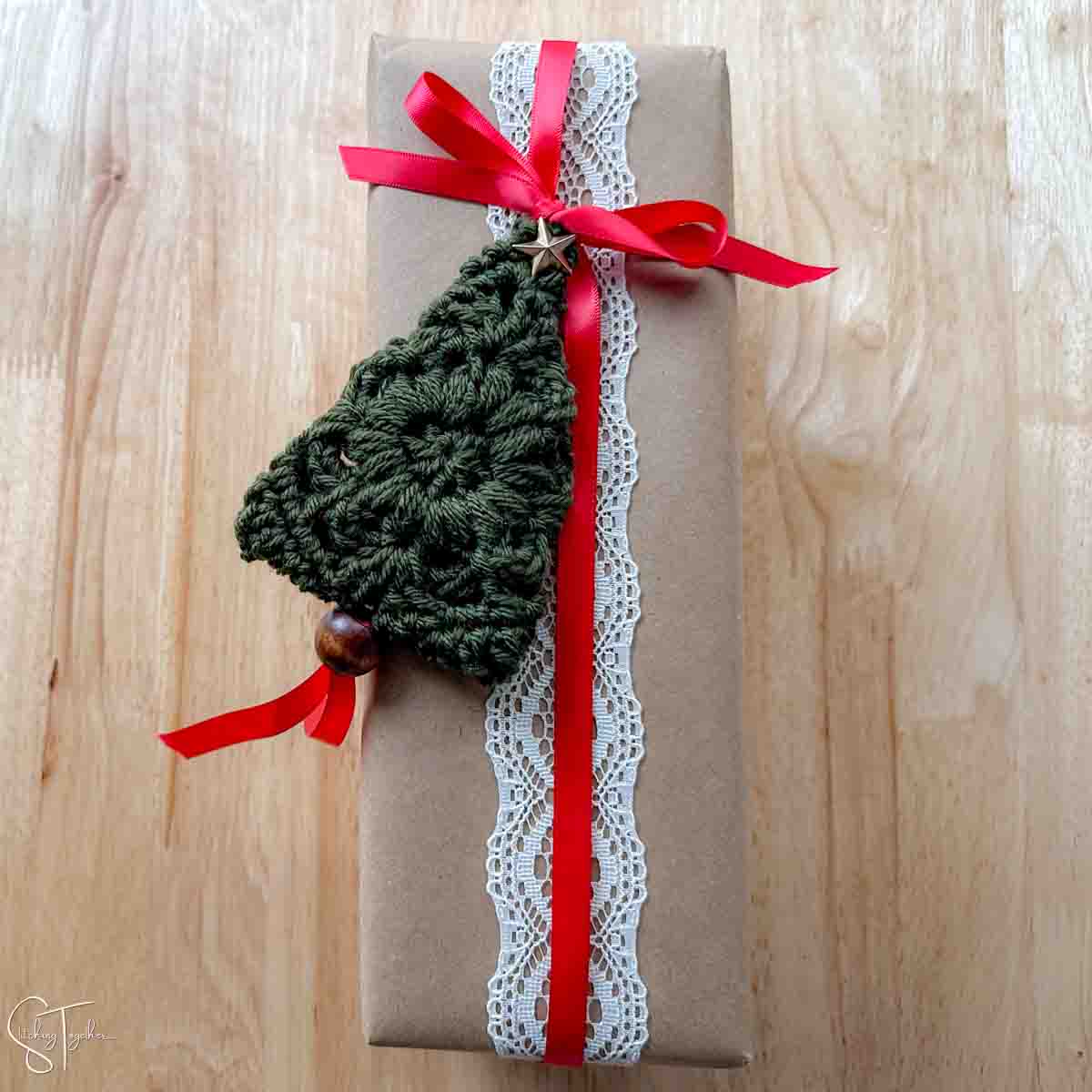 Granny square Christmas tree  laying flat on top of a present.