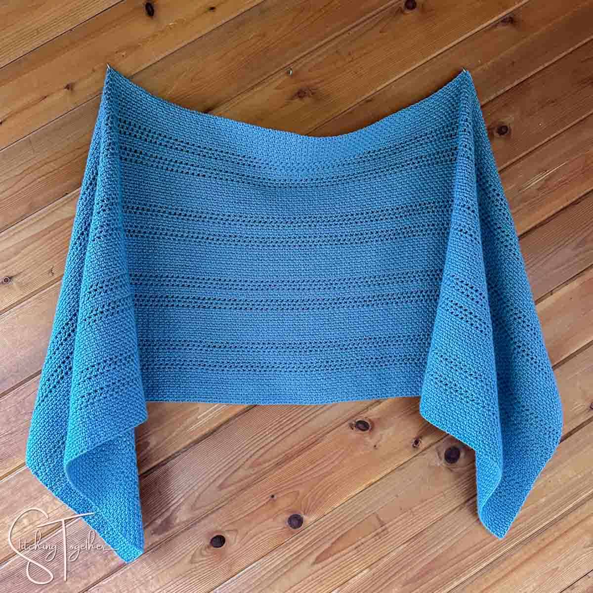 rectangular crochet shawl hanging on a wall
