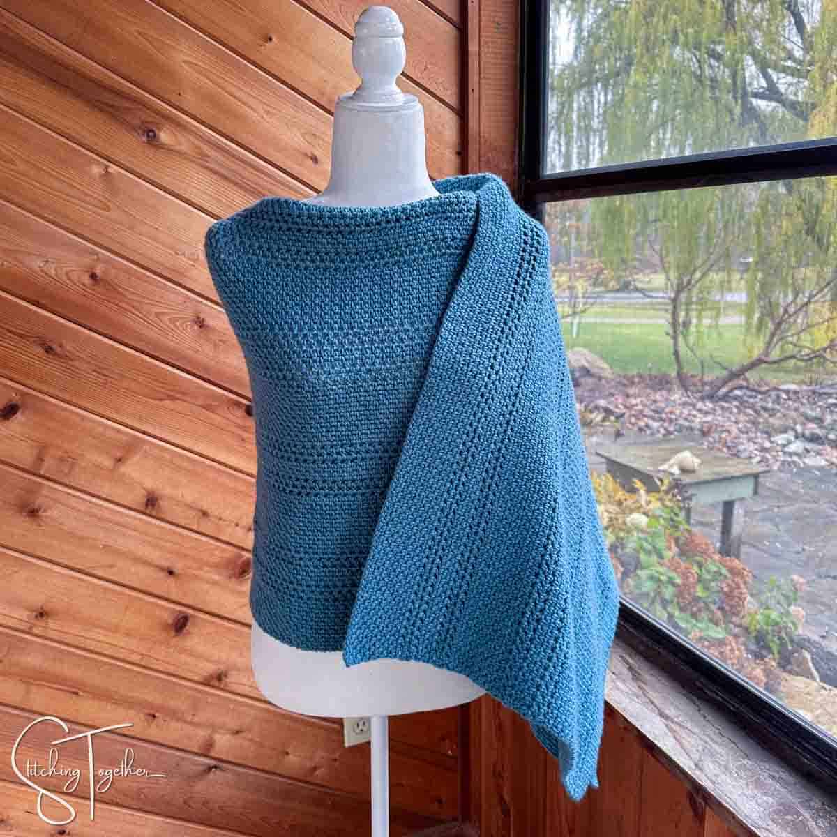 blue crochet shawl wrapped around a mannequin