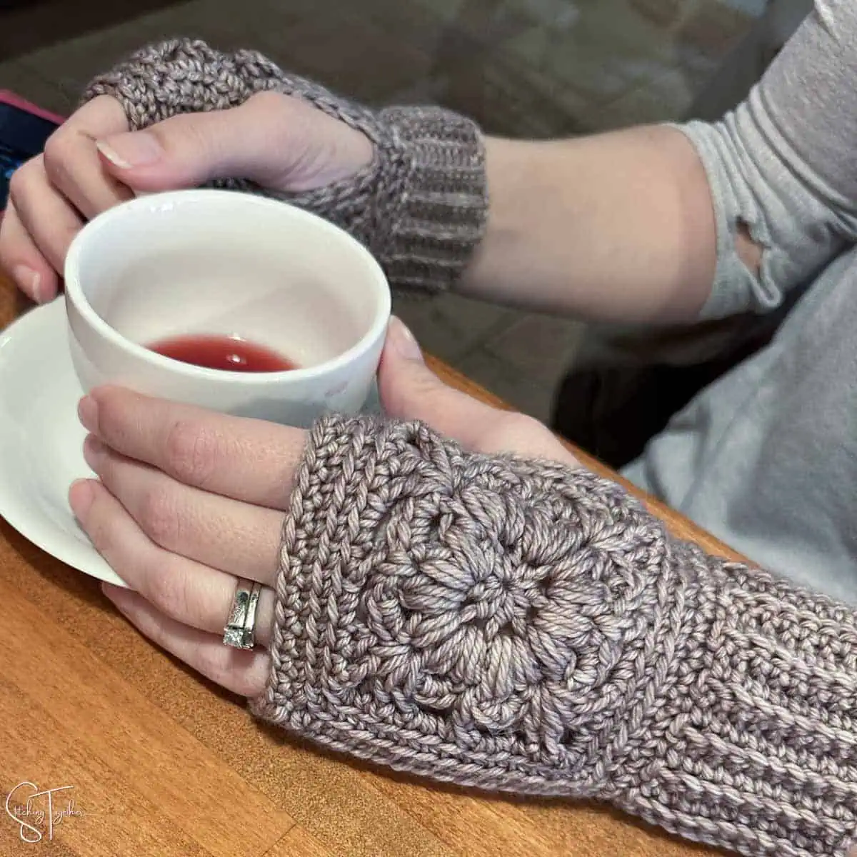 close up of handing holding teacup and wearing crochet wrist warmers