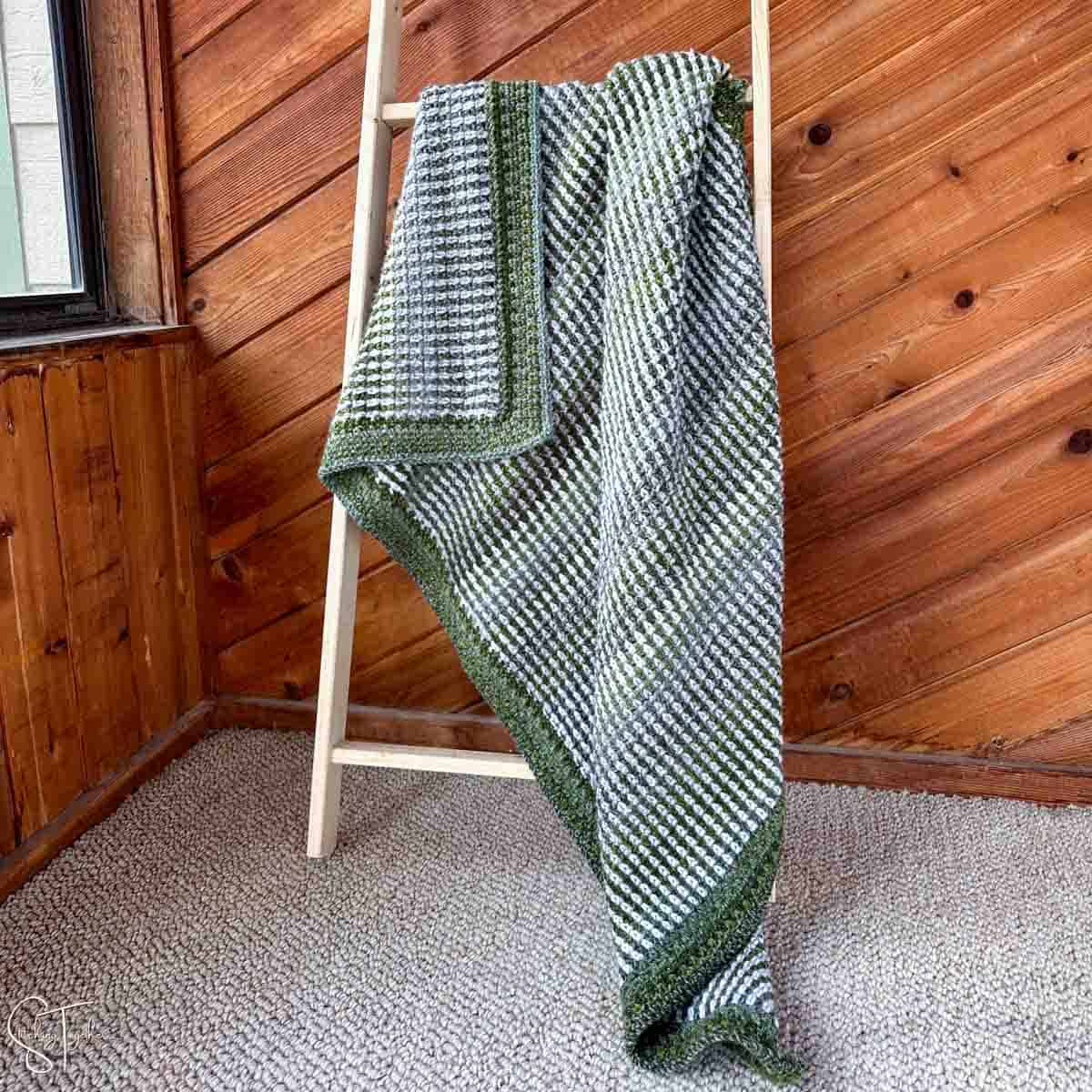 green moss stitch blanket hanging on a blanket ladder