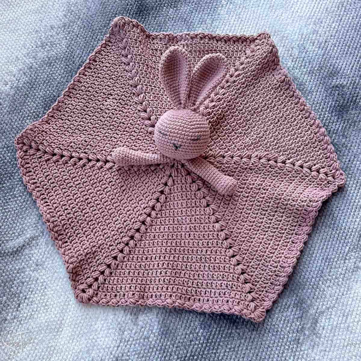 a crochet bunny security blanket laid out