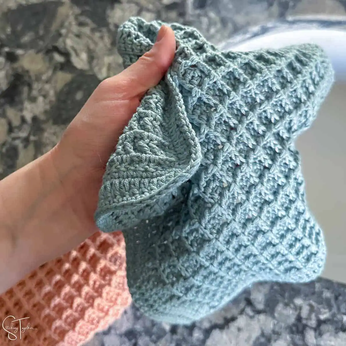 hand holding a blue crochet waffle stitch washcloth