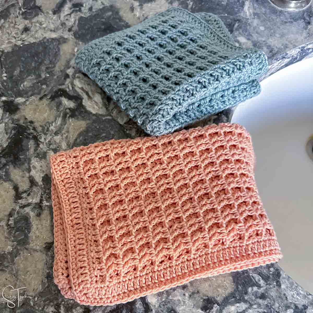 two crochet washcloths folded next to a bathroom sink