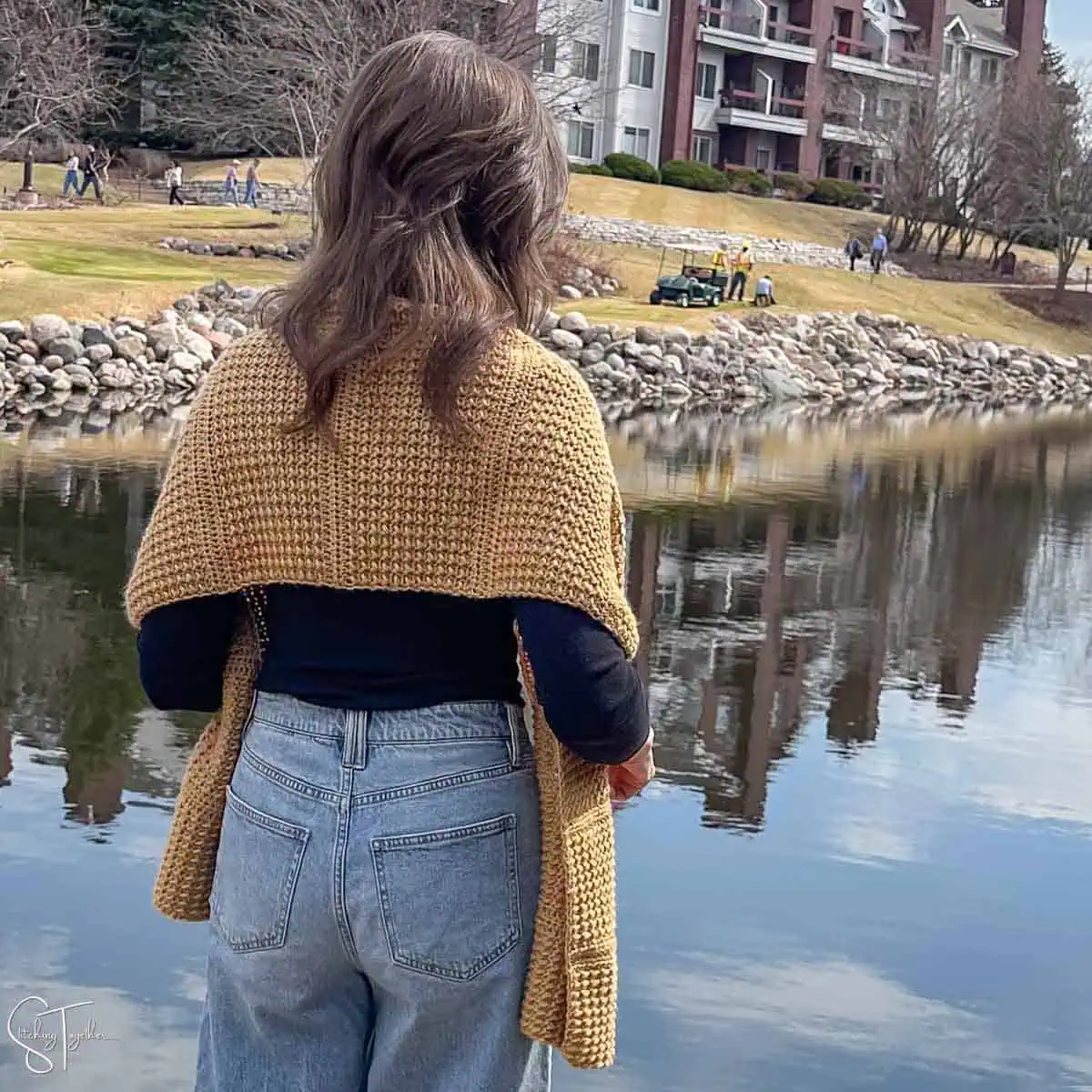 view of the back of a crochet shawl wrapped around a woman's shoulders