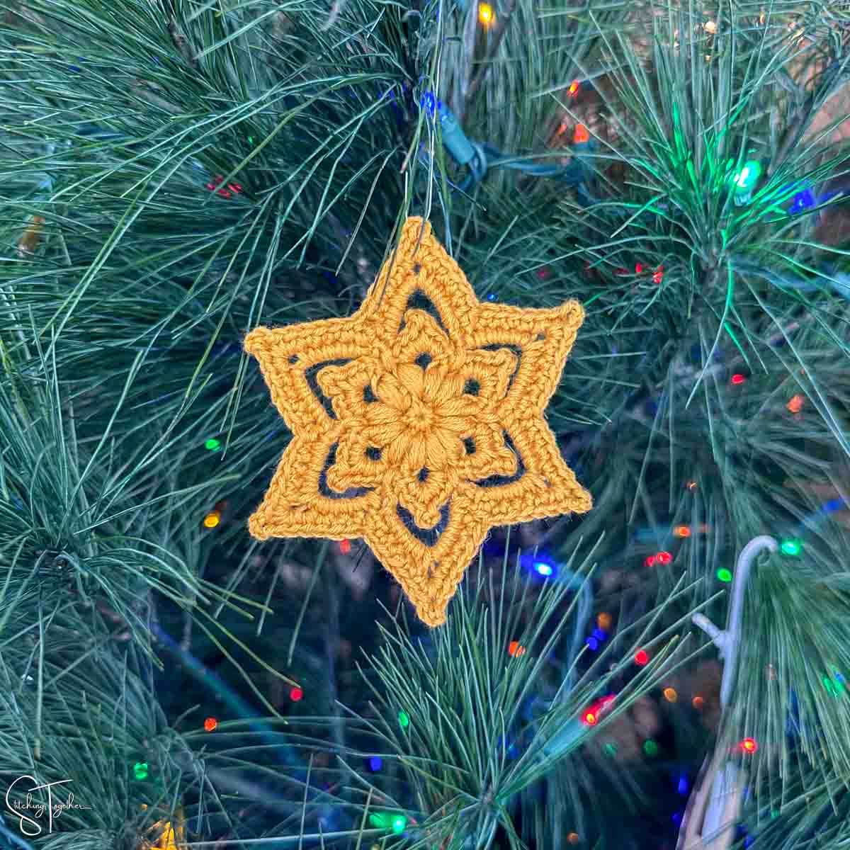 crochet star ornament hanging on a Christmas tree