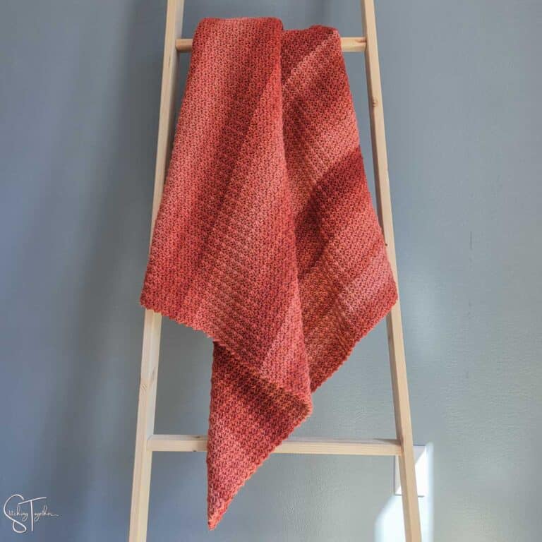 striped orange crochet blanket draped on a ladder