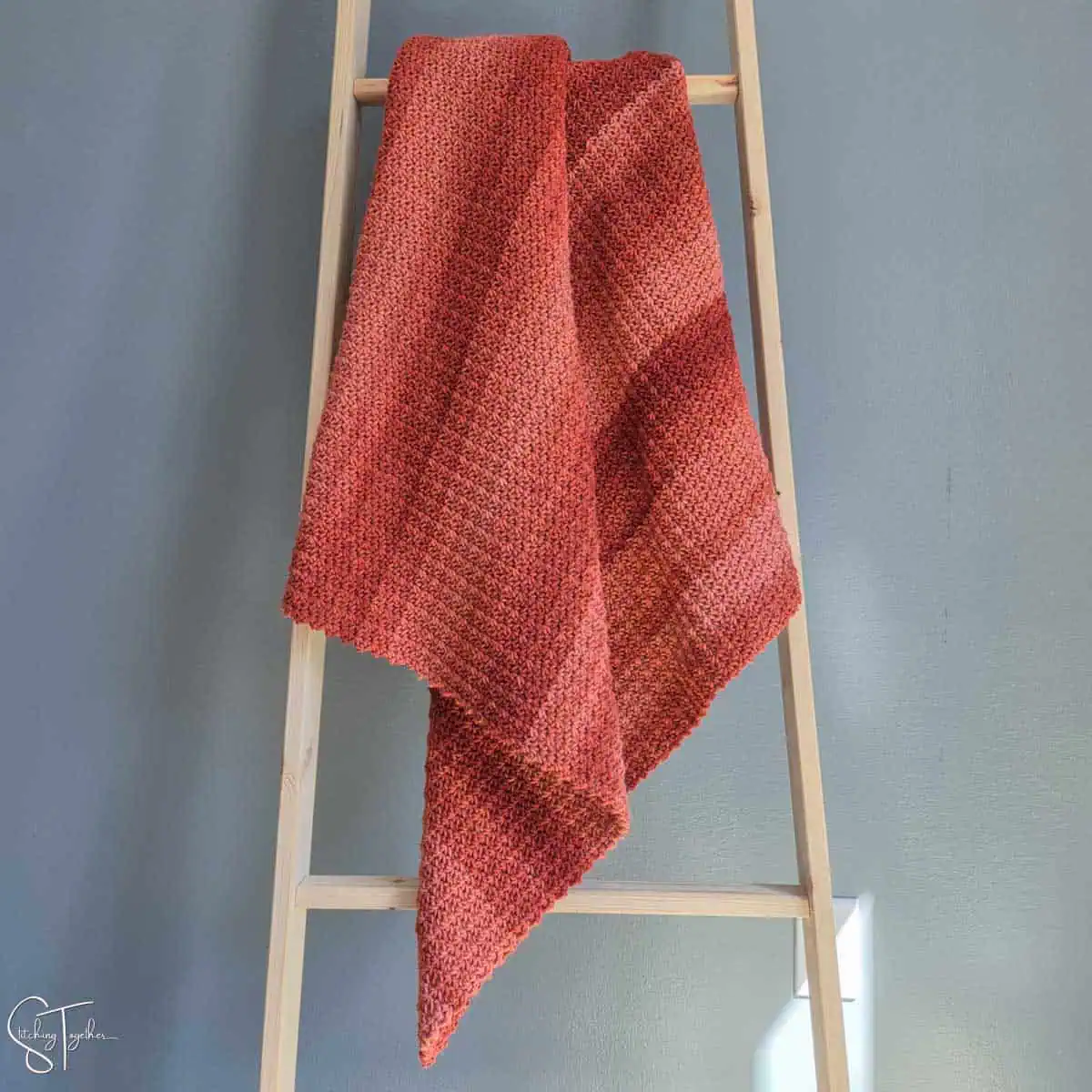 striped orange crochet blanket draped on a ladder