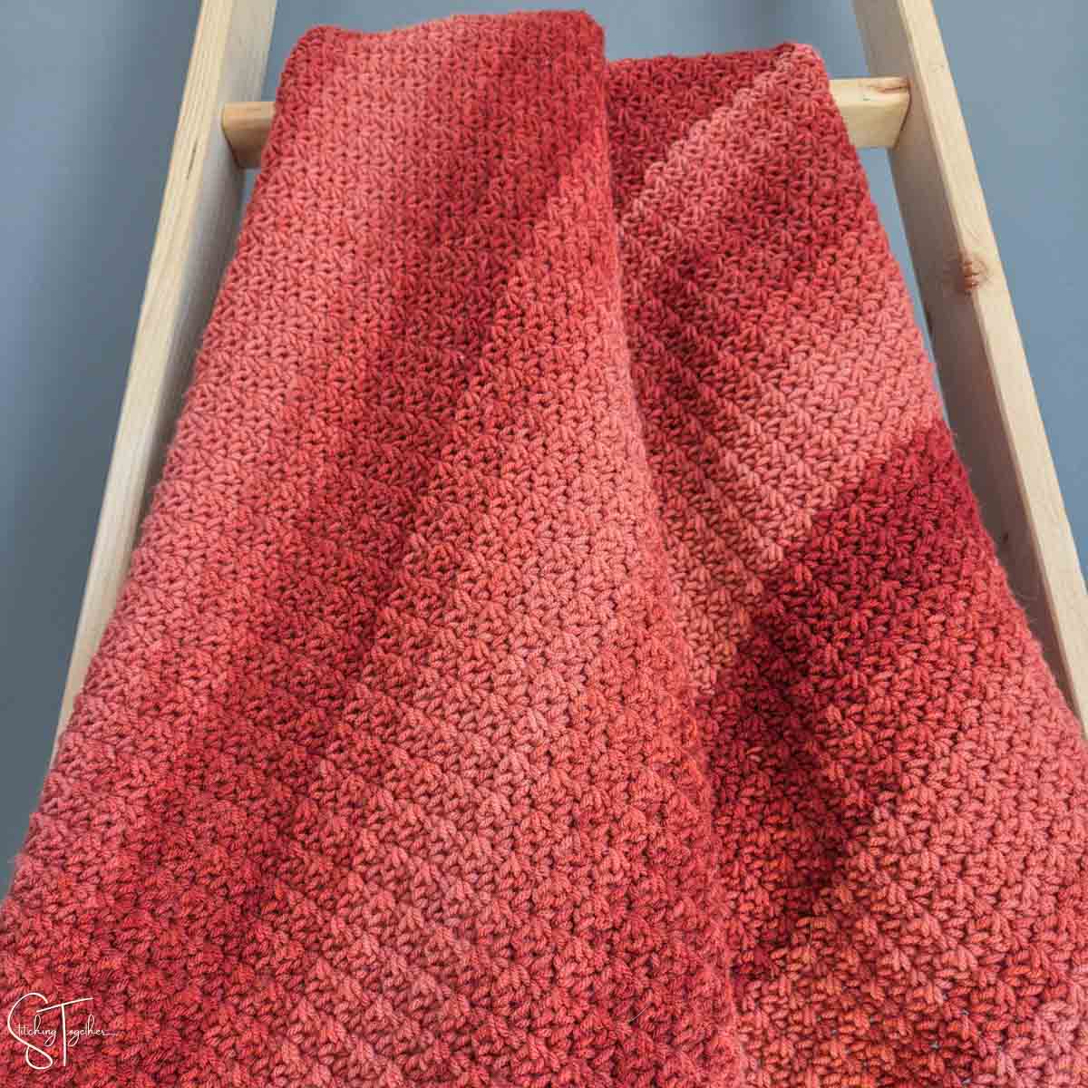 striped orange crochet throw draped on a ladder