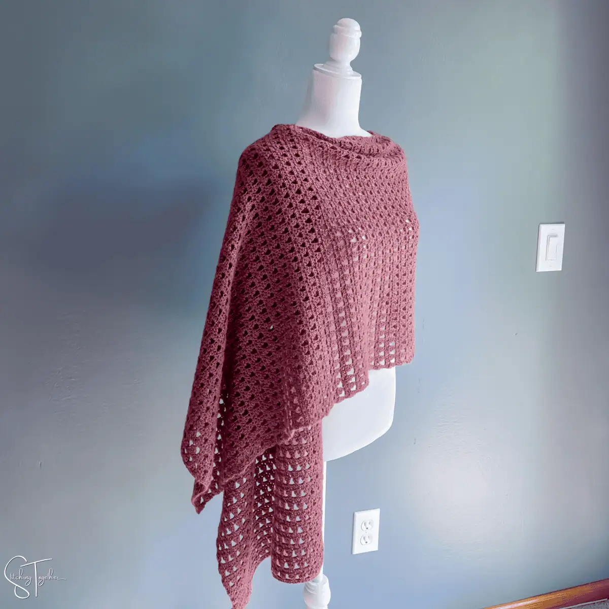 lightweight crochet shawl draped on the shoulders of a mannequin